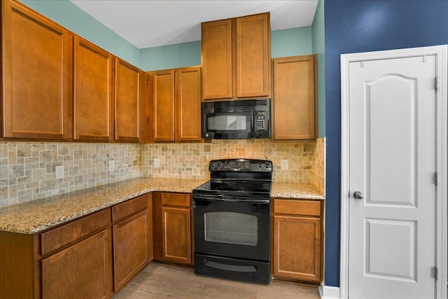 kitchen featuring black appliances, decorative backsplash, light stone countertops, and light hardwood / wood-style flooring