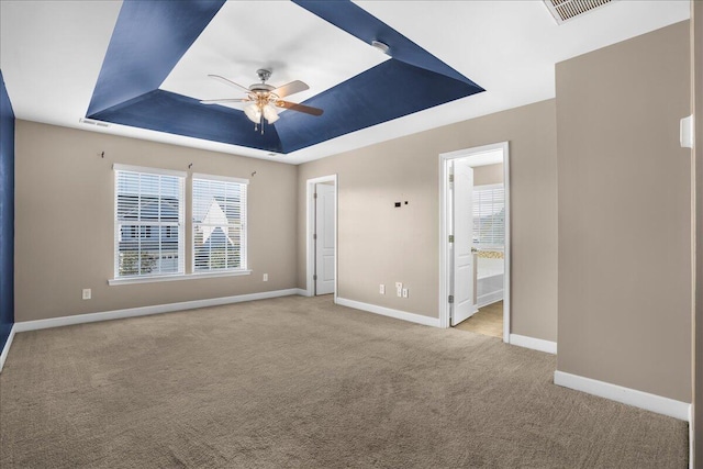 carpeted empty room with ceiling fan and a tray ceiling