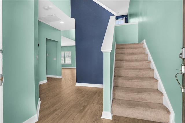 staircase with hardwood / wood-style floors and a towering ceiling