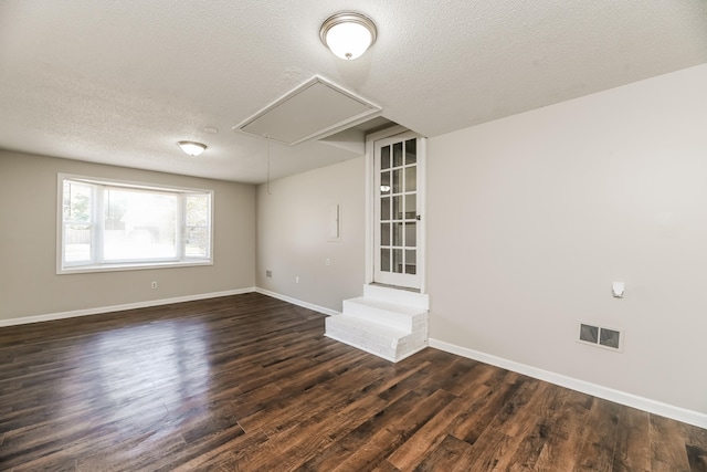 spare room with a textured ceiling and dark hardwood / wood-style floors