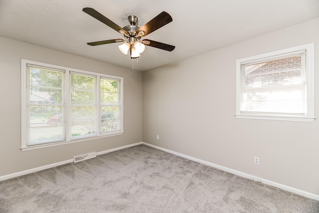 empty room featuring light carpet, a textured ceiling, and ceiling fan