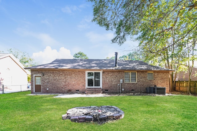 rear view of house with central air condition unit and a lawn