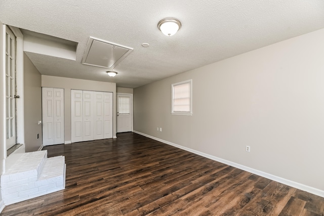 unfurnished bedroom featuring multiple closets, a textured ceiling, and dark hardwood / wood-style floors