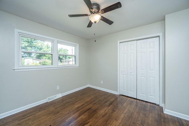 unfurnished bedroom with ceiling fan, dark wood-type flooring, and a closet