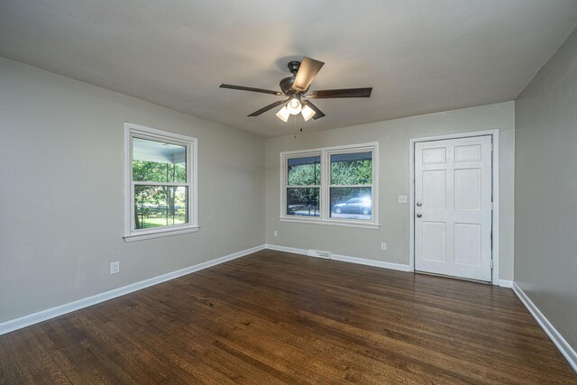 empty room featuring plenty of natural light, ceiling fan, and dark hardwood / wood-style flooring