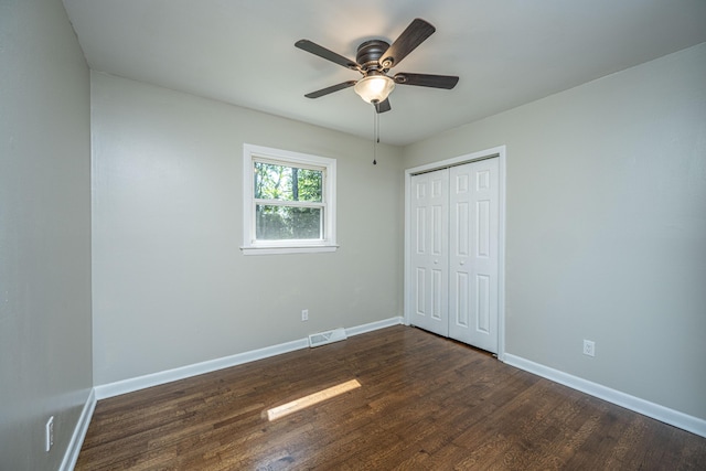 unfurnished bedroom featuring ceiling fan, a closet, and dark hardwood / wood-style flooring