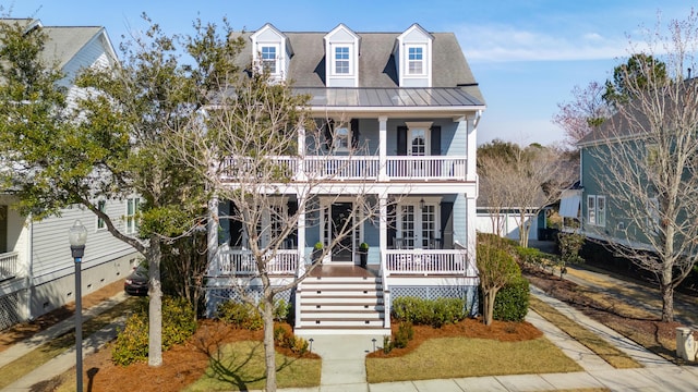 view of front of home featuring a balcony, stairway, metal roof, covered porch, and a standing seam roof