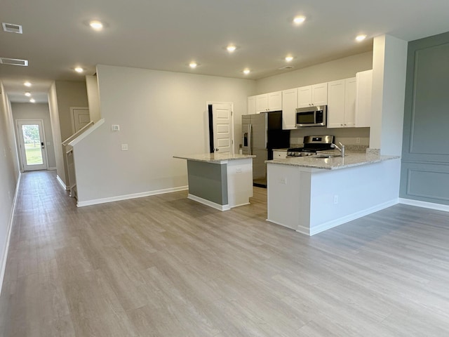 1443 Central Ave, Summerville, SC 29483 - kitchen with stainless steel appliances, light wood-style flooring, light stone countertops, white cabinetry, and recessed lighting