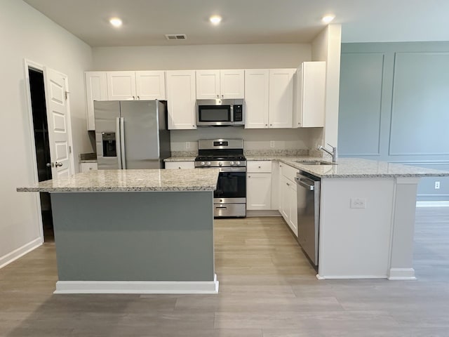 1443 Central Ave, Summerville, SC 29483 - kitchen with stainless steel appliances, a sink, a center island, white cabinetry, and light wood finished floors
