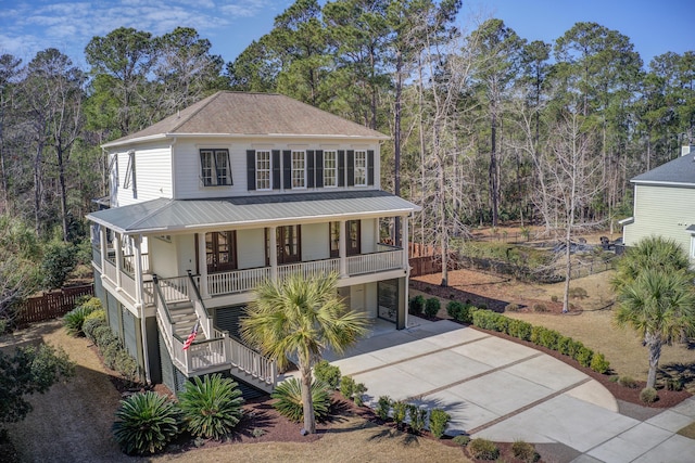 view of front of property featuring covered porch, stairway, metal roof, and concrete driveway