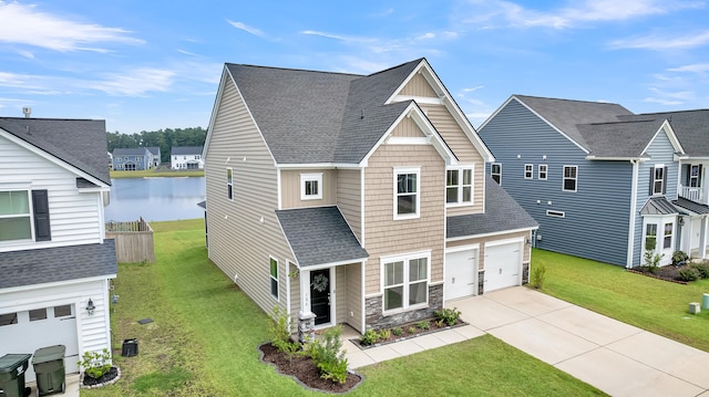 view of front of house with a front yard, a garage, and a water view