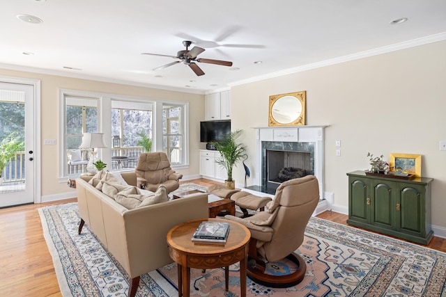 living area with light wood finished floors, a fireplace, baseboards, and crown molding