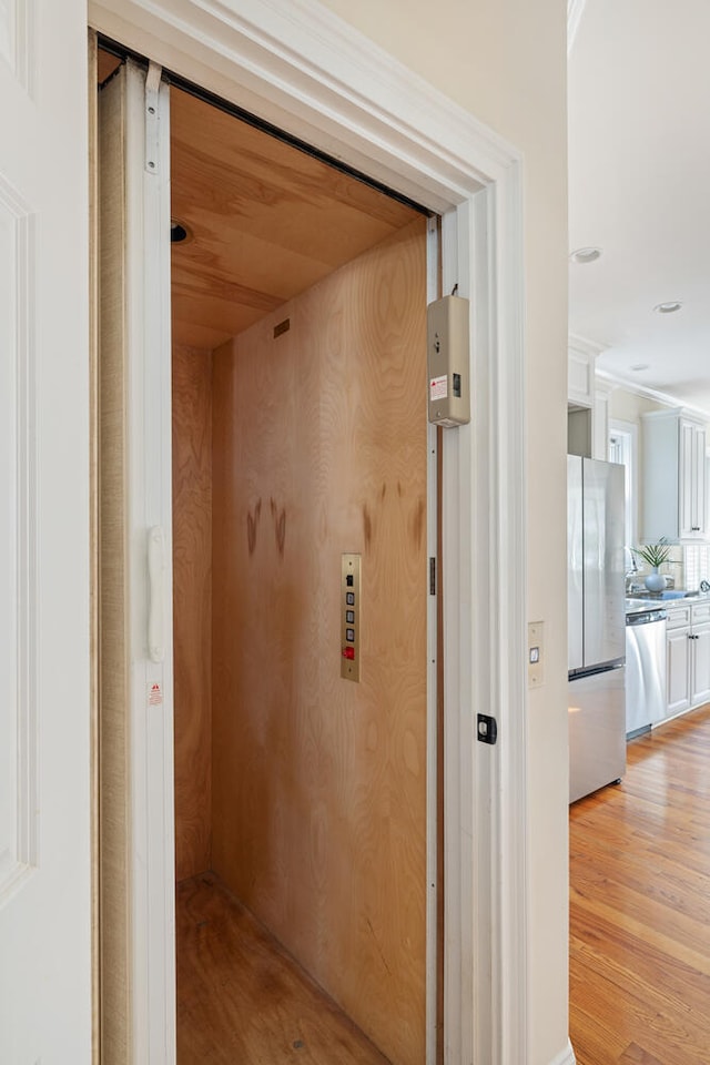 hall with light wood-style floors and elevator