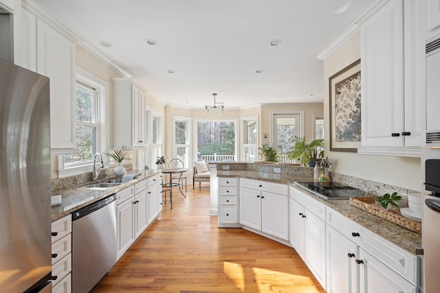 kitchen featuring appliances with stainless steel finishes, white cabinets, a sink, and a peninsula