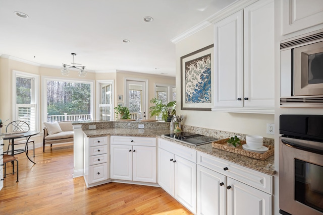 kitchen featuring a peninsula, white cabinetry, stainless steel appliances, and crown molding