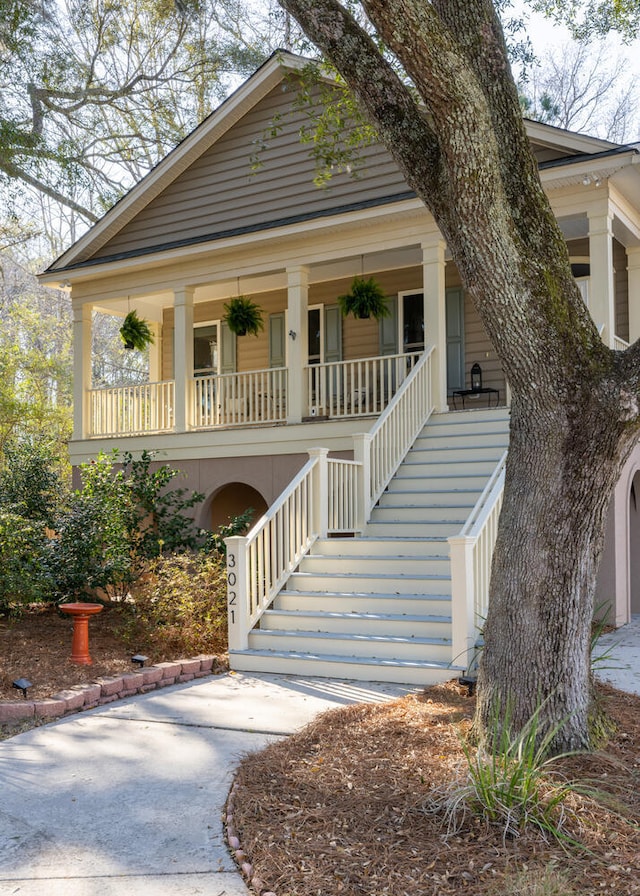 view of front facade featuring covered porch, driveway, and stairway