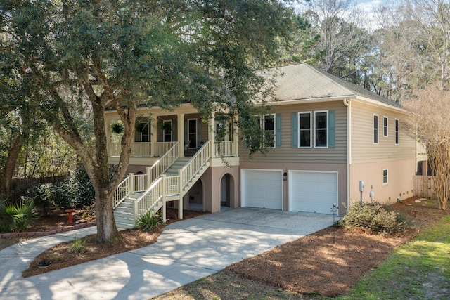 raised beach house featuring covered porch, driveway, stairway, and stucco siding