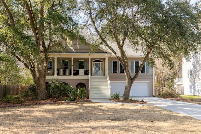 view of front of house with concrete driveway, stairway, an attached garage, fence, and a porch