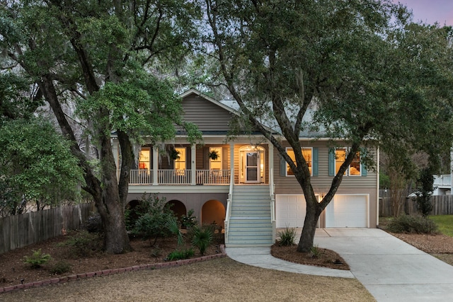 view of front of home with a porch, fence, a garage, driveway, and stairs