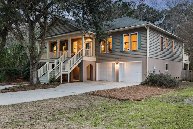 beach home with stucco siding, a porch, a garage, driveway, and stairs