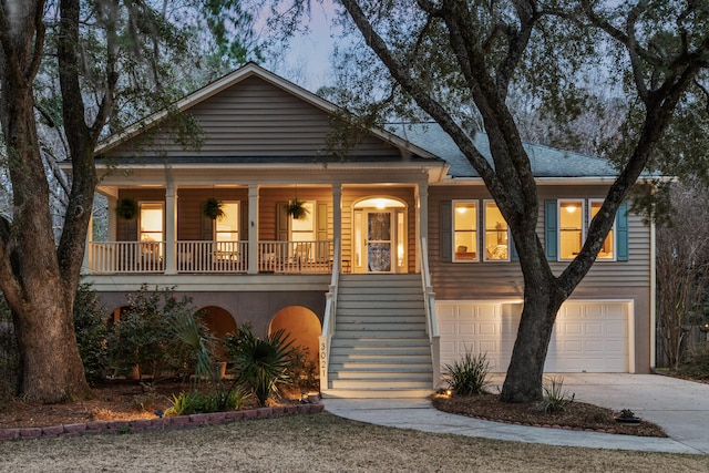 view of front of home featuring covered porch, concrete driveway, an attached garage, and stairs