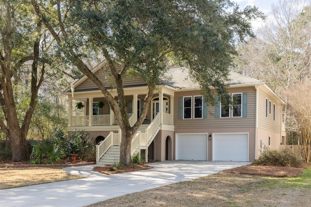 beach home with an attached garage, covered porch, stairs, driveway, and stucco siding