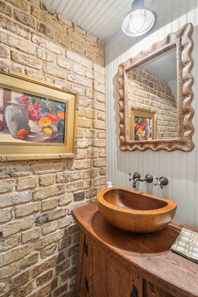 bathroom with vanity and brick wall