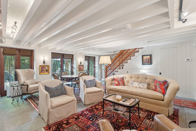 living room with wooden walls, french doors, and beam ceiling