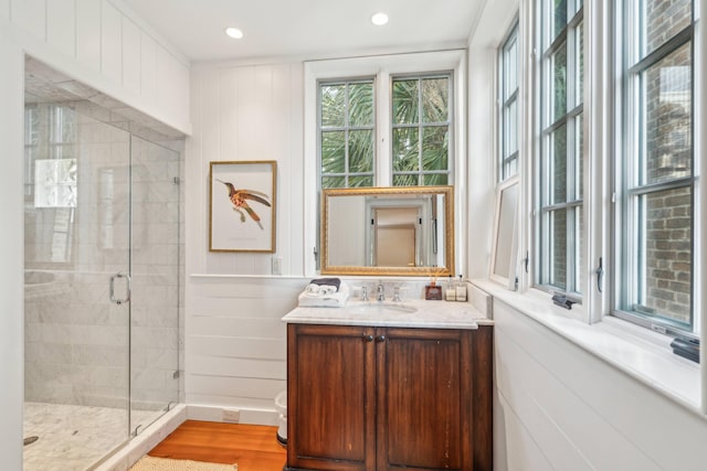 bathroom with walk in shower, wood walls, vanity, and wood-type flooring