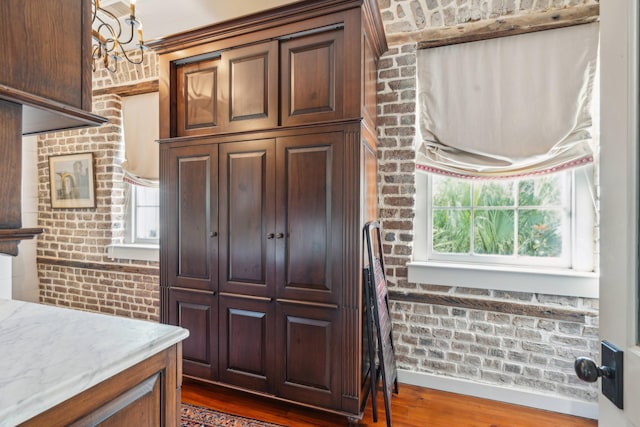 kitchen featuring dark wood-type flooring, a healthy amount of sunlight, and brick wall