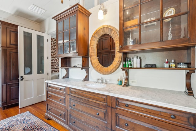 kitchen with pendant lighting, light hardwood / wood-style floors, sink, and light stone counters