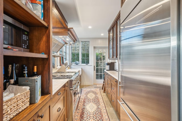 kitchen with wall chimney exhaust hood, premium appliances, and light tile patterned floors