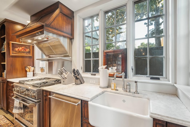 kitchen featuring light stone countertops, appliances with stainless steel finishes, and sink