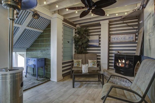 sitting room with a lit fireplace, wood finished floors, and beam ceiling