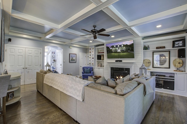 living area featuring arched walkways, coffered ceiling, dark wood finished floors, and a high end fireplace