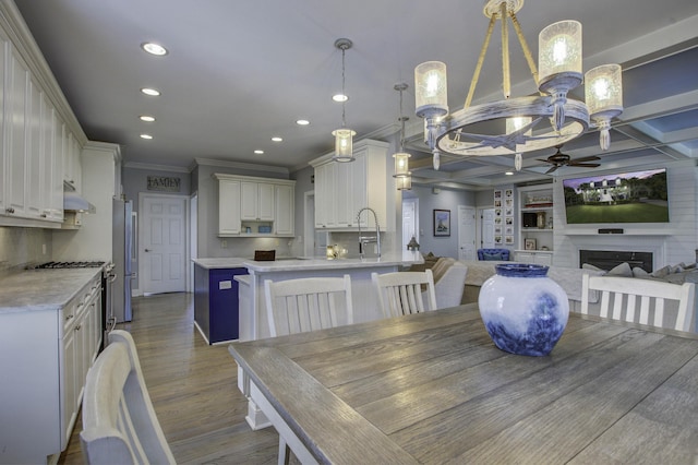 dining area with recessed lighting, coffered ceiling, light wood-style floors, a fireplace, and ceiling fan with notable chandelier