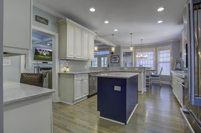 kitchen featuring decorative light fixtures, ornamental molding, a kitchen island, dishwasher, and a peninsula