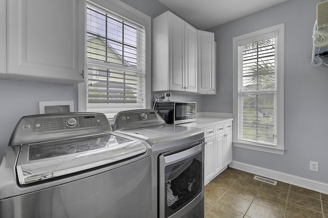 washroom featuring a healthy amount of sunlight, cabinet space, visible vents, and washer and dryer