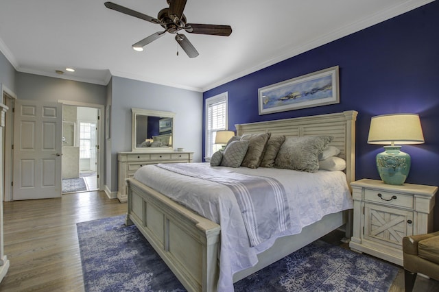 bedroom with ornamental molding, multiple windows, baseboards, and wood finished floors