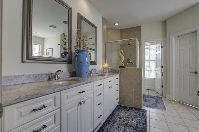 bathroom with double vanity, a stall shower, a sink, and tile patterned floors