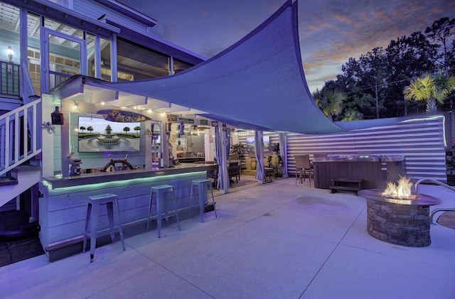 view of patio / terrace featuring a fire pit, a bar, and a hot tub