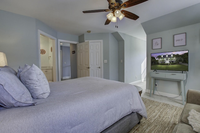 carpeted bedroom featuring a ceiling fan, ensuite bath, and baseboards