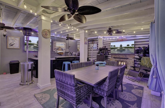 dining area with light wood finished floors, an outdoor brick fireplace, and beam ceiling