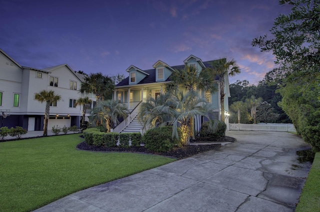 view of front of home featuring driveway, a garage, stairway, fence, and a yard