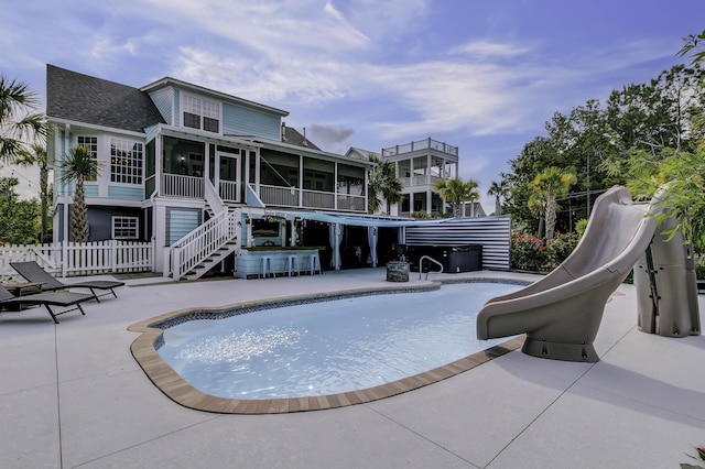 pool with a patio, a water slide, fence, and a sunroom