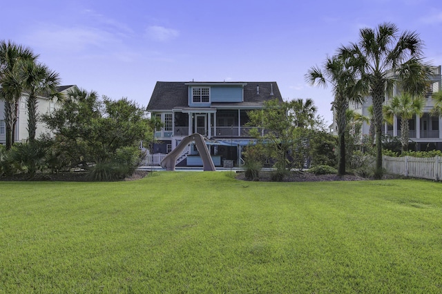 back of property with a sunroom, fence, and a lawn