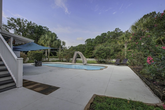 view of pool with a fenced in pool, a water slide, a patio area, and stairway