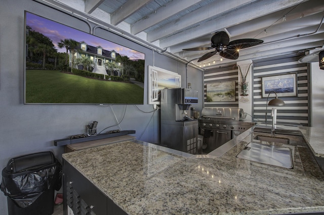 kitchen with a ceiling fan, beam ceiling, a sink, and light stone countertops