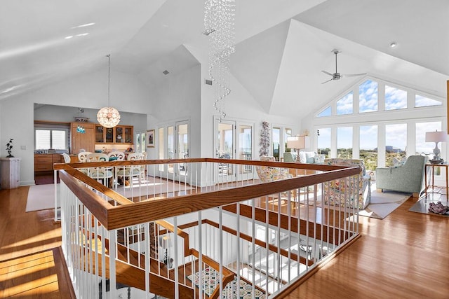 hall with high vaulted ceiling, wood finished floors, a notable chandelier, and an upstairs landing