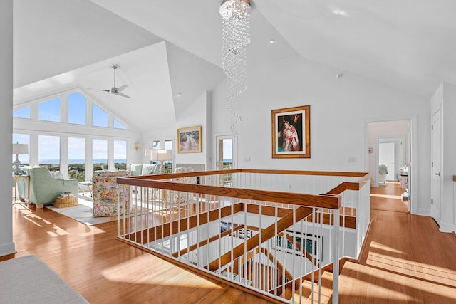 hallway featuring a chandelier, high vaulted ceiling, wood finished floors, and an upstairs landing